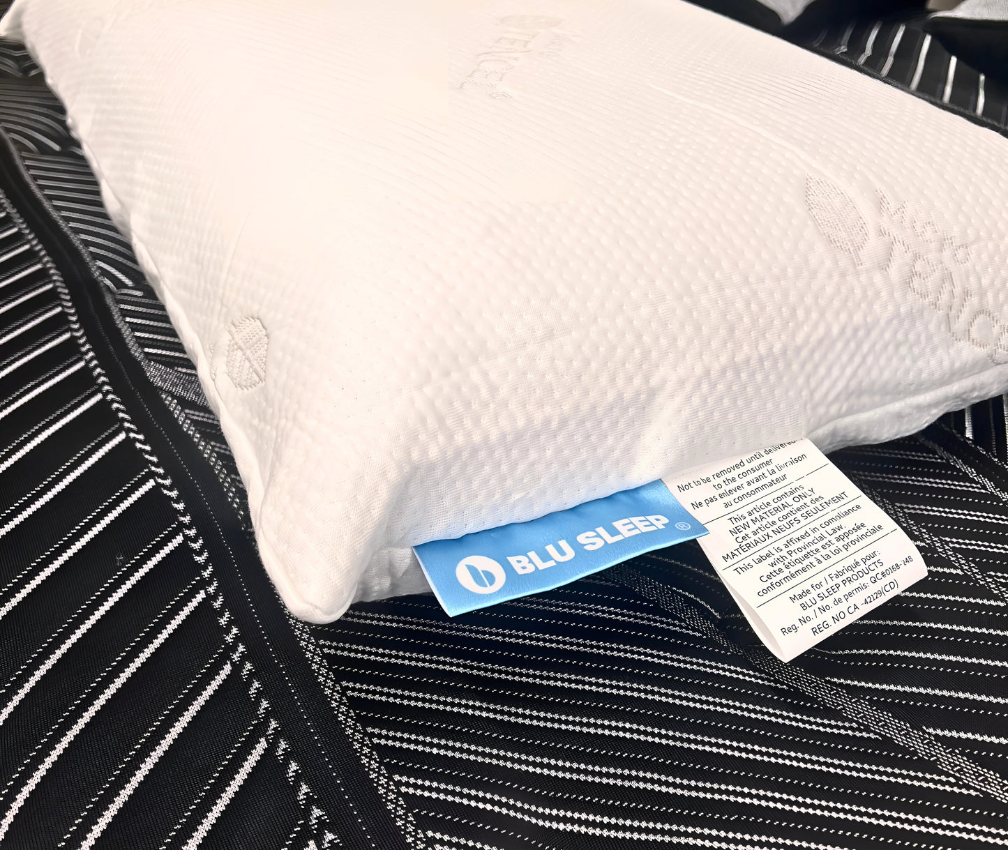 White pillow with BLU SLEEP tag on a black mattress