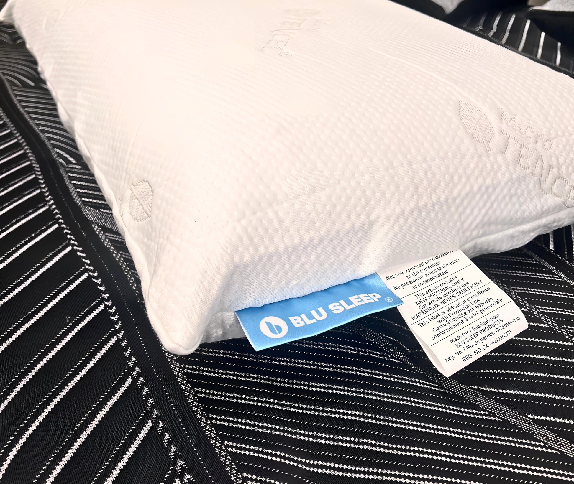 White pillow with BLU SLEEP tag on a black mattress