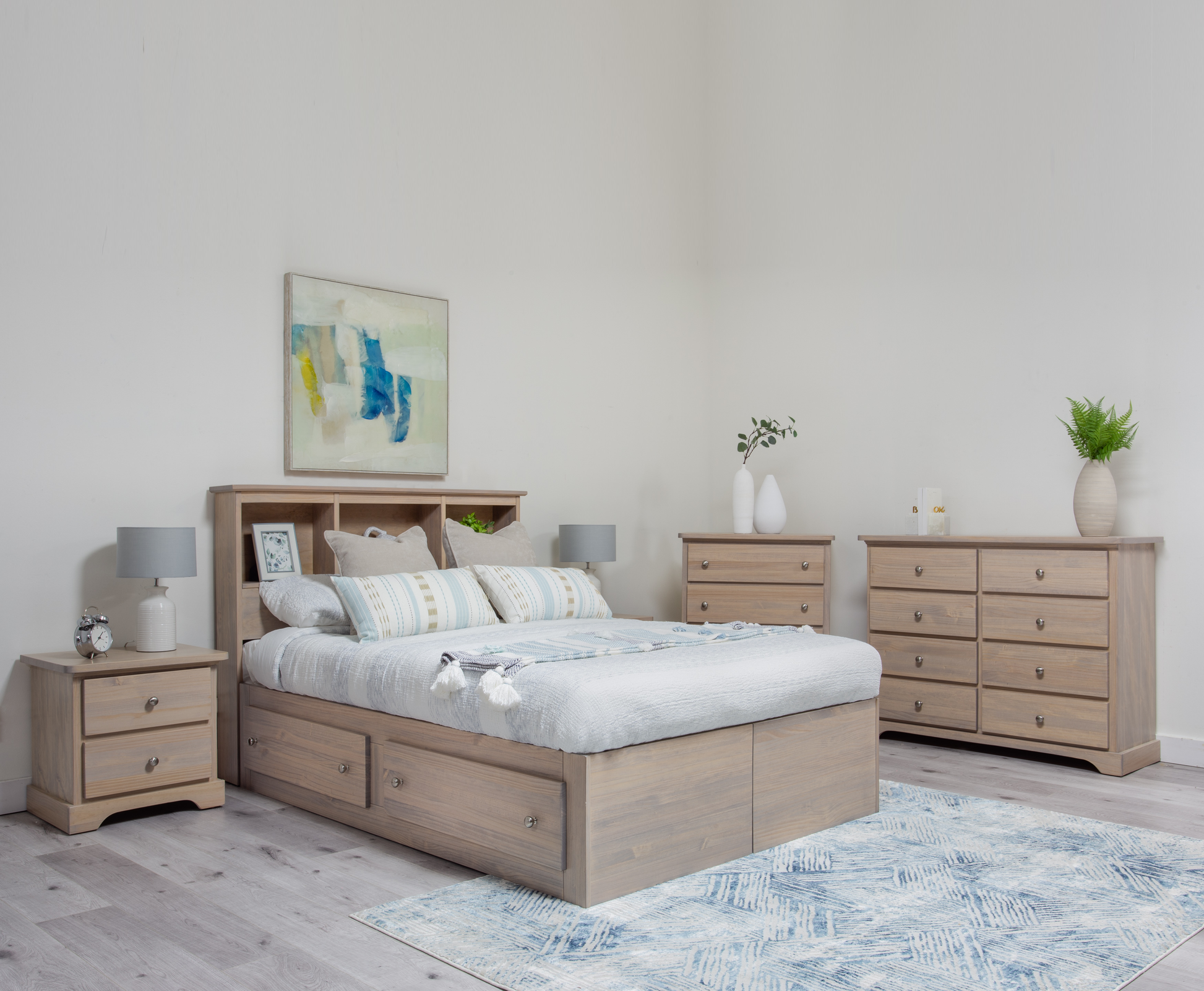 A solid wood storage bed with headboard, in a bedroom setting, with the bed partially dressed with bedding and a decorative mattress pad.