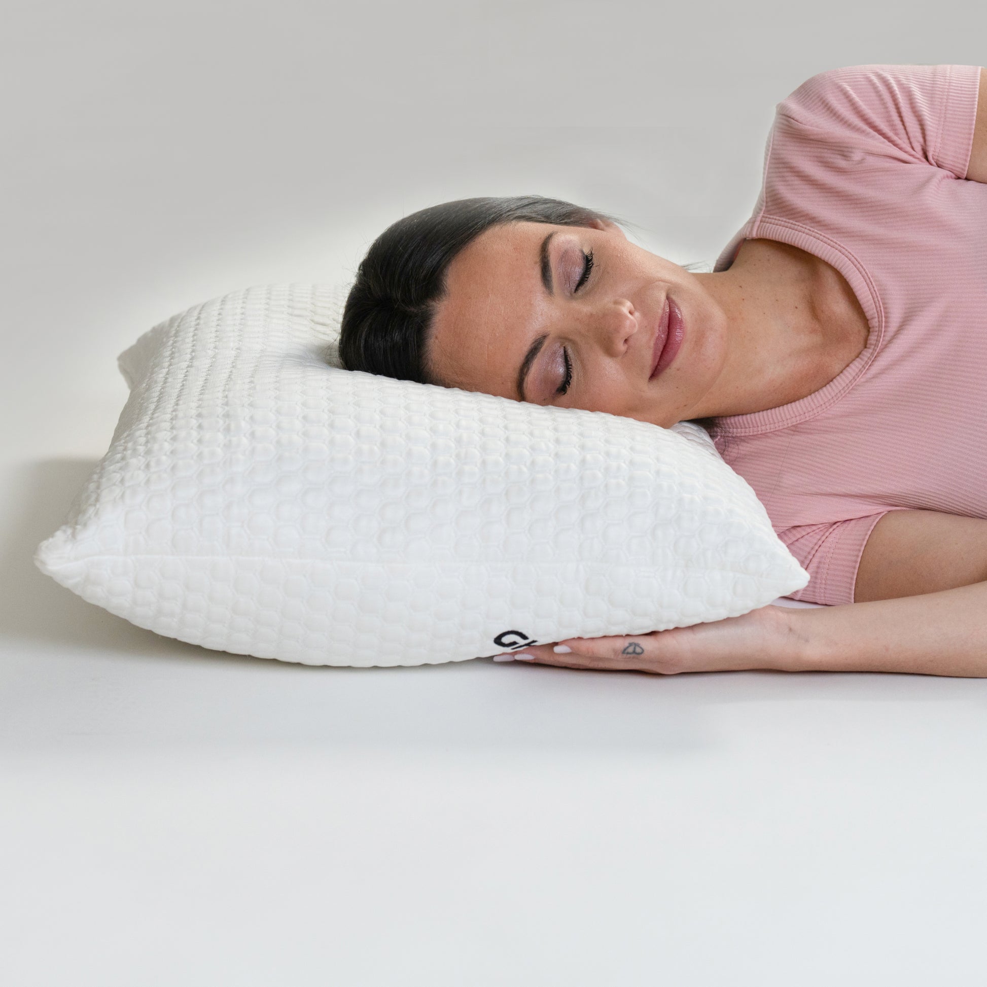 Woman lying on a white GhostBed pillow with a neutral background