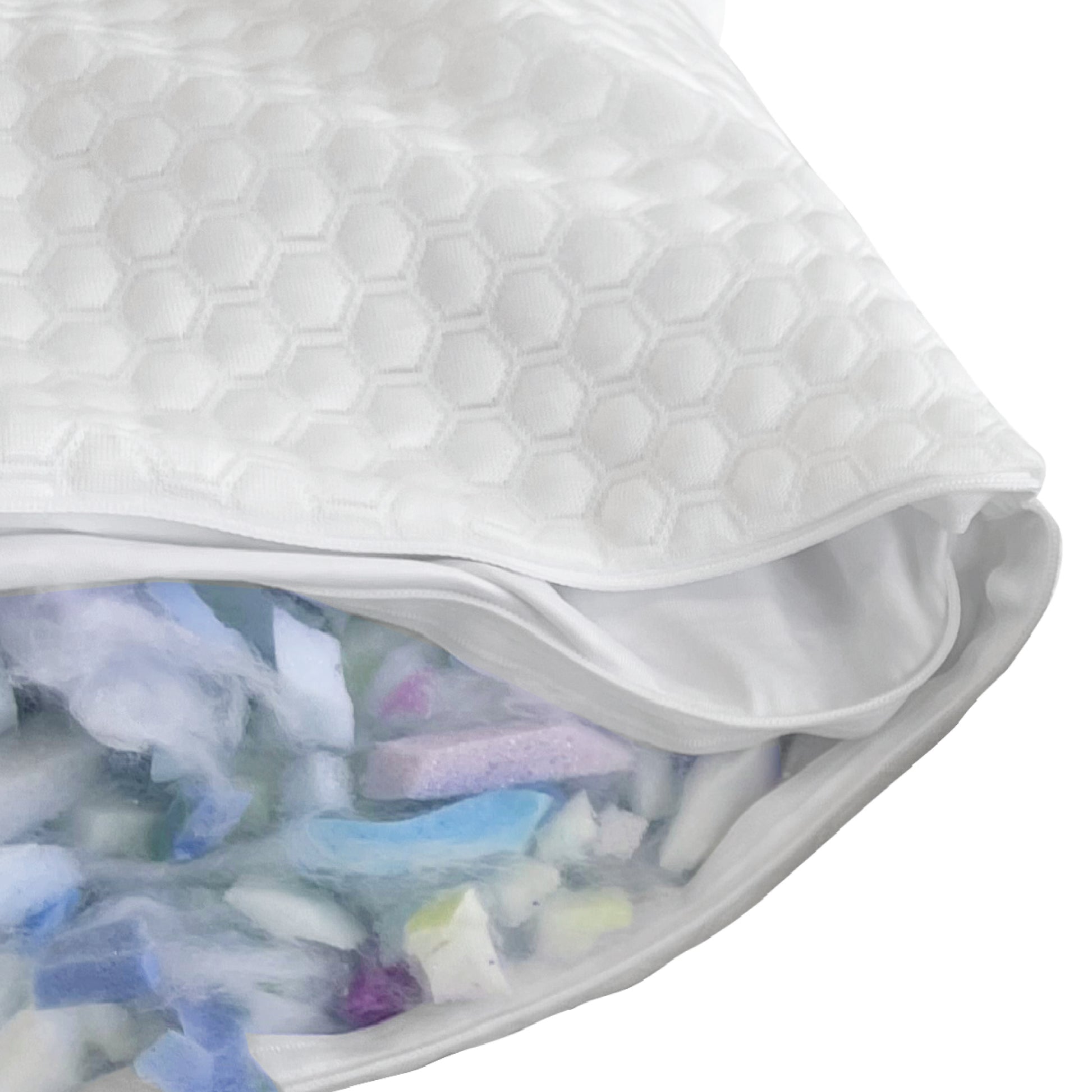 Close-up of GhostBed white pillow with a textured surface, showing a small opening revealing colorful items inside.