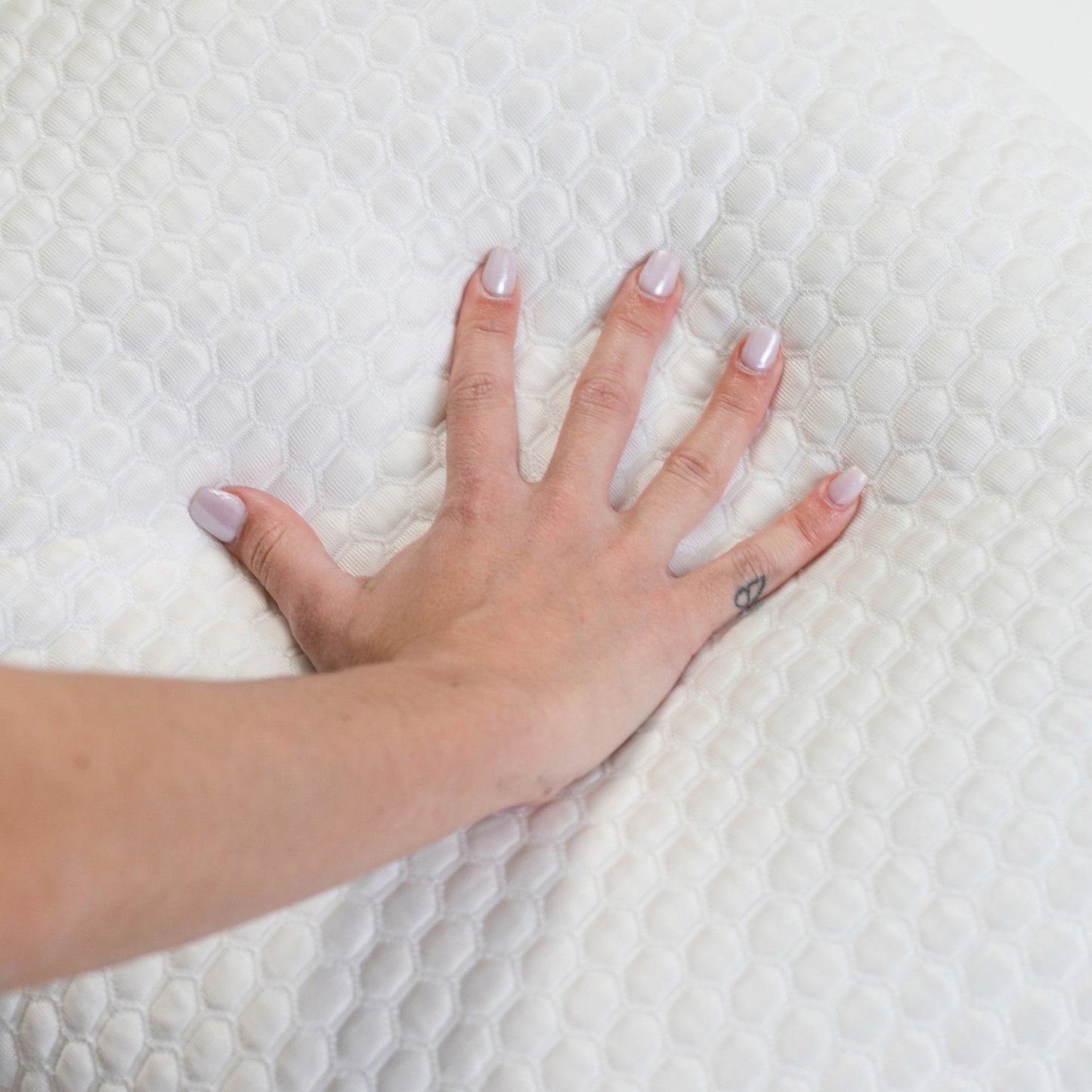Hand on a textured white ghostbed pillow