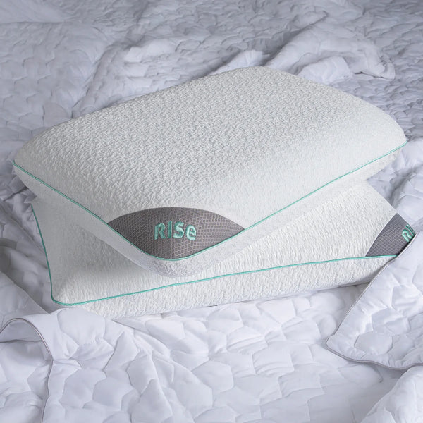 White pillow with 'RISE' branding on a textured gray surface