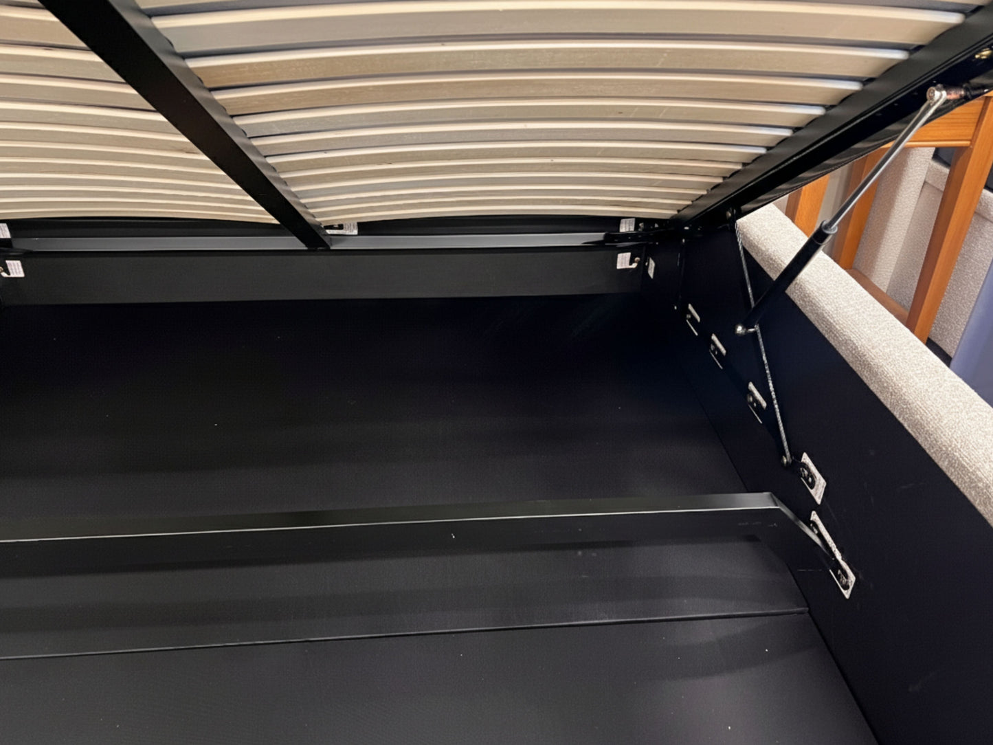 Bed with a black frame and mattress, featuring a wooden headboard.