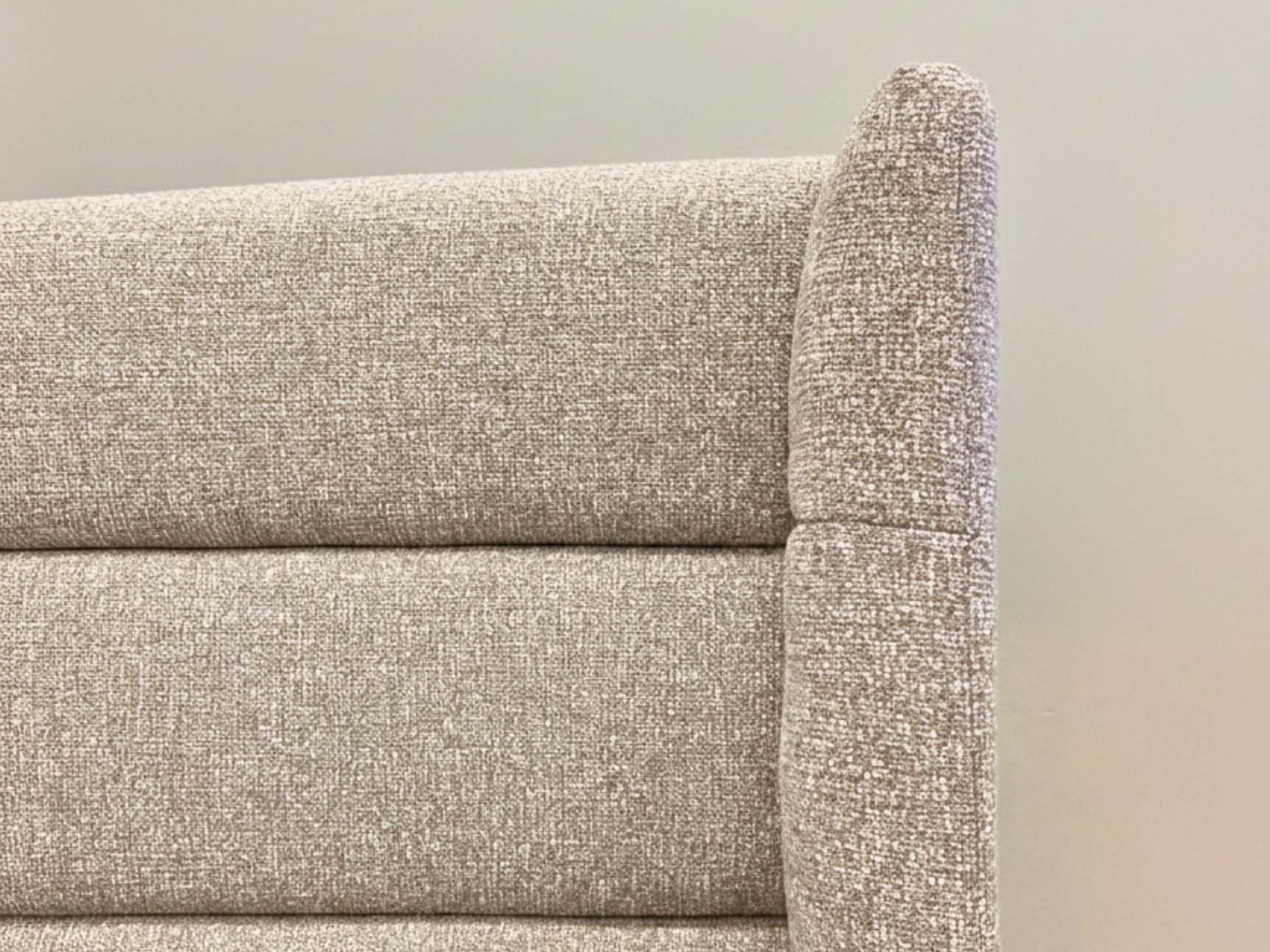 Close-up of a textured beige sofa corner against a neutral background