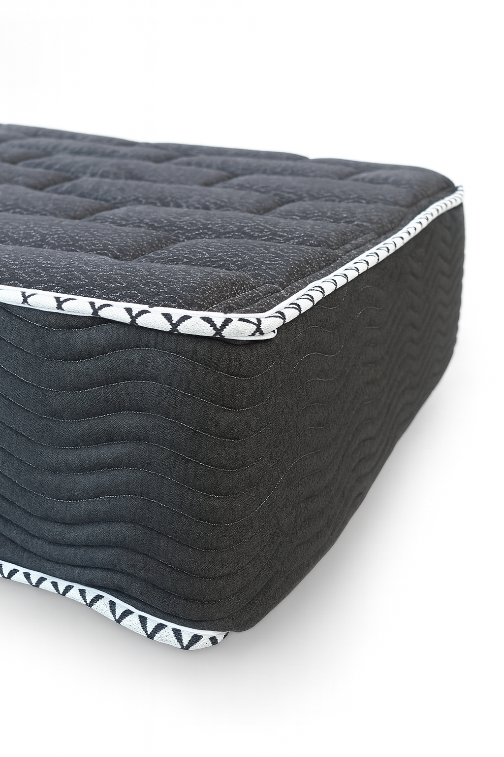 Angled close-up of King Koil Spine Support 11-inch tight top mattress with white patterned piping and charcoal wavy-stitched sides.